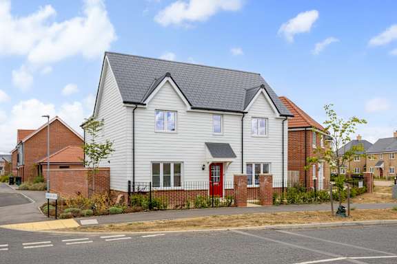 A white house with a red door is situated in a residential area.