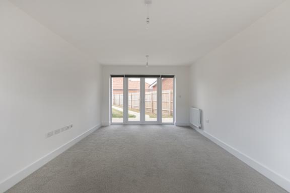 A large empty room with a grey carpet and white walls.
