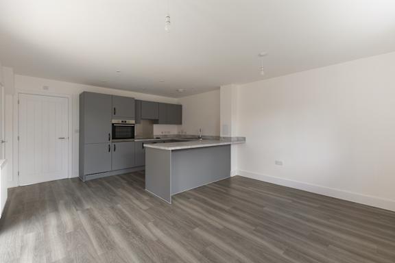 A kitchen with a grey island and wooden flooring.