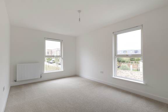 A white room with two windows and a radiator.