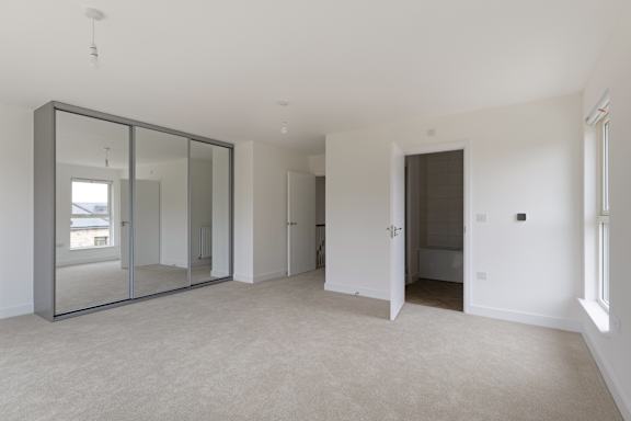 A large empty room with a glass wardrobe and a white door.