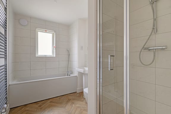 A white bathroom with a tub and a walk in shower.