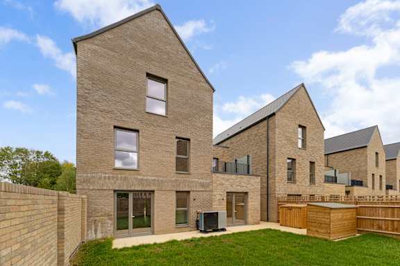 A modern house with a brick exterior and a green lawn in front.