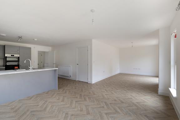 A spacious room with a herringbone patterned floor and white walls.