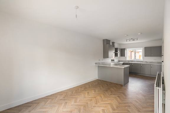 A kitchen with a wooden floor and white walls.