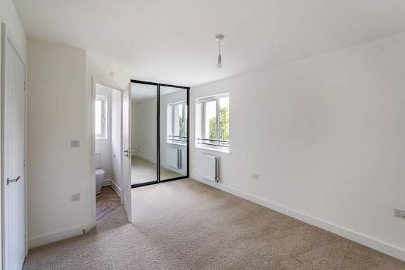 A white room with a carpet floor and a window.