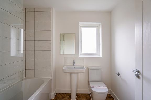 A white bathroom with a tub, sink, toilet and mirror.