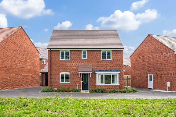 A red brick house with a green lawn in front.