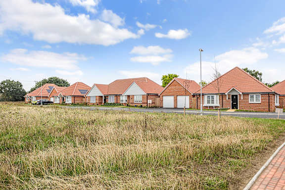 A row of houses with a grassy field in front.