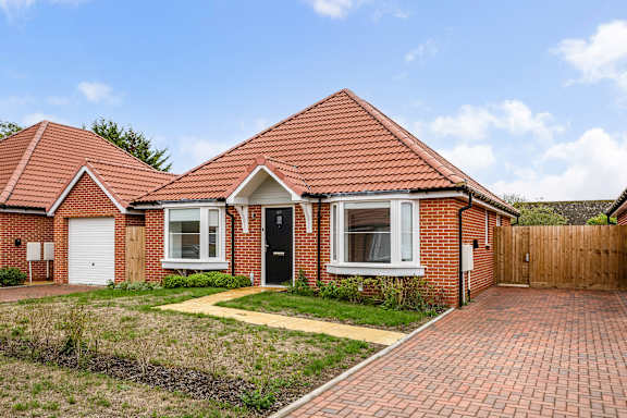 A red brick house with a black door and white windows.