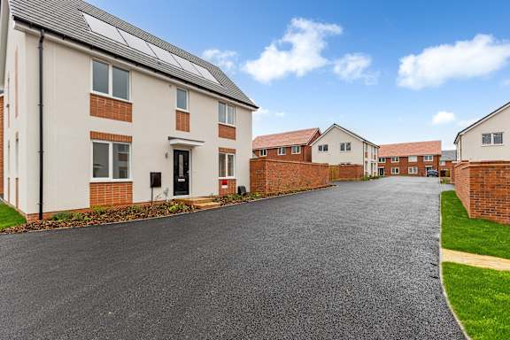A row of houses with a driveway in the foreground.