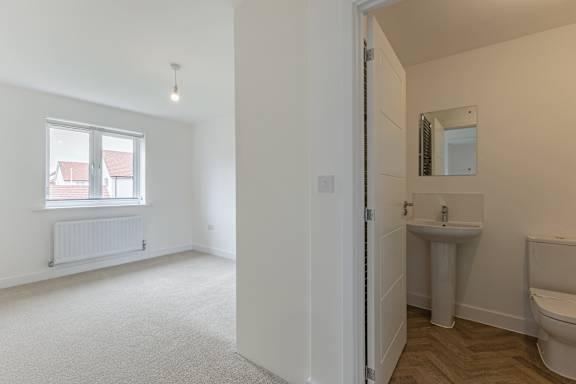 A white bathroom with a toilet, sink, and window.