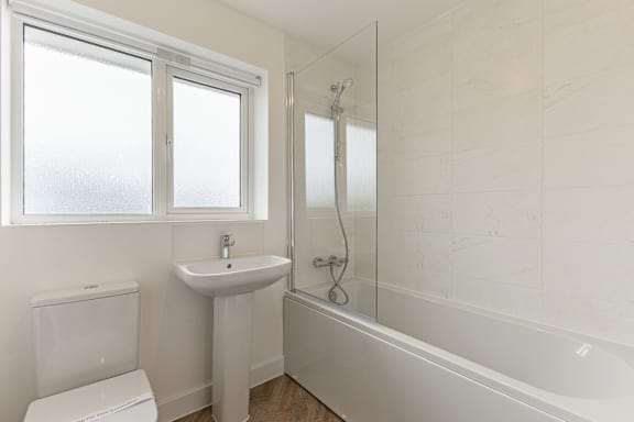 A white bathroom with a toilet, sink, and bathtub.