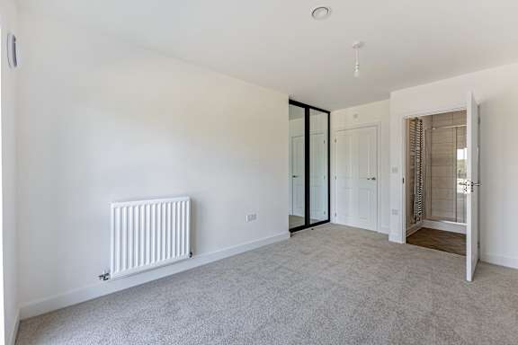 A white room with a radiator and carpeted floor.