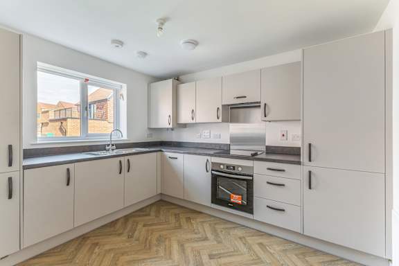 A kitchen with white cabinets and a wooden floor.