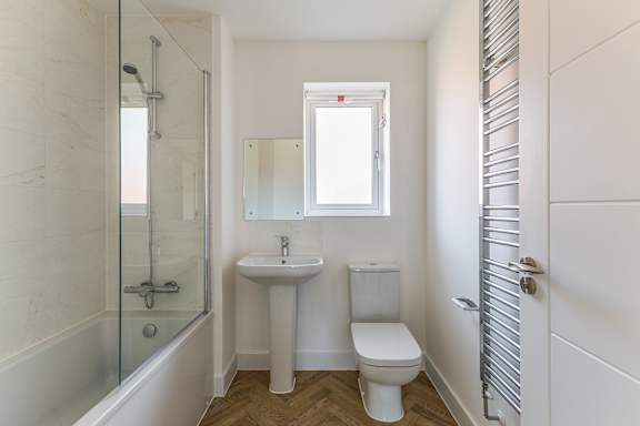 A white bathroom with a toilet, sink, and shower.