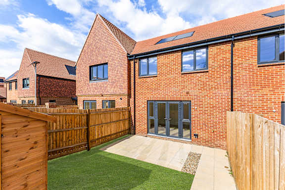 A red brick house with a wooden fence and a green lawn.
