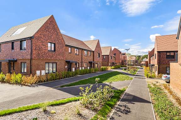 A row of red brick houses with a pathway in between.