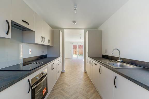 A kitchen with white cabinets and black countertops.