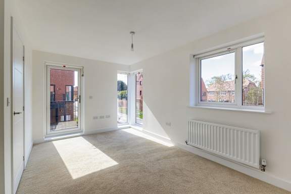A room with a white wall and a window with a view of a red building.