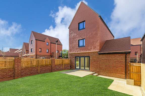 A red brick house with a green lawn in front.