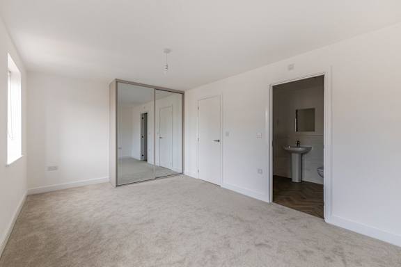 A large empty room with a sink and mirror.