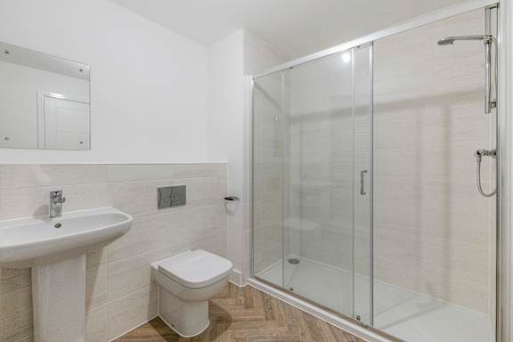 A white toilet sits in a bathroom next to a sink and a walk-in shower.