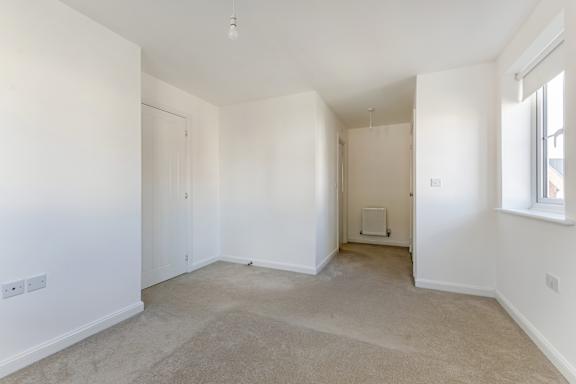 A spacious room with beige carpeting and white walls.