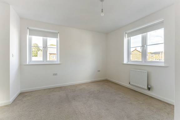 A white room with a window and a radiator on the wall.
