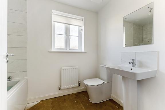 A white bathroom with a toilet, sink, and window.