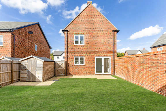 A red brick house with a white door and a small garden.