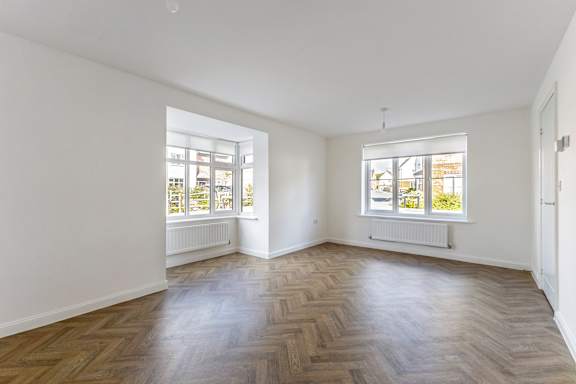 A room with wooden flooring and white walls.
