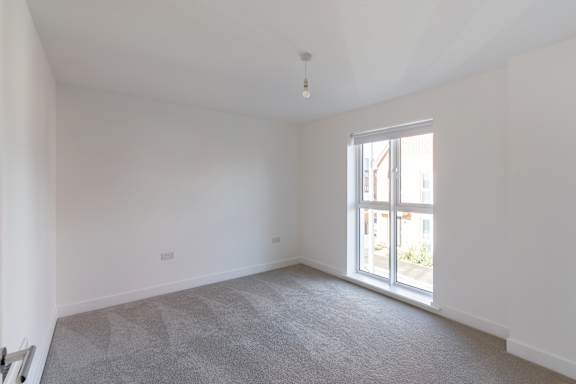 A room with a carpeted floor and a window.