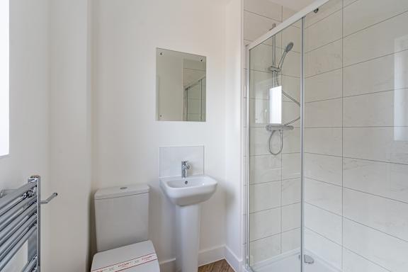 A white bathroom with a sink, mirror, and toilet.