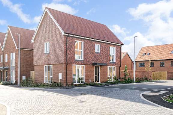 A red brick house with a driveway in front.