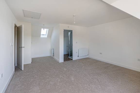 A spacious room with carpeted floor and white walls.