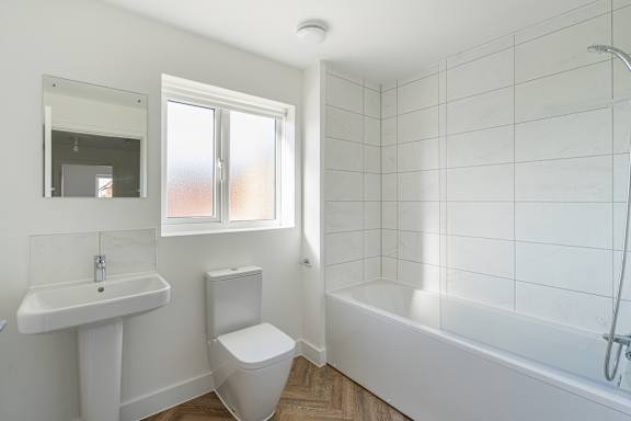 A white bathroom with a toilet, sink, and bathtub.