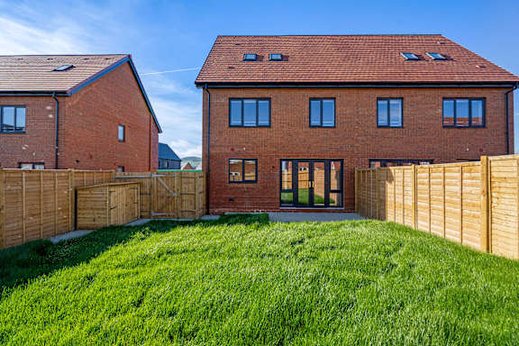 A red brick house with a green lawn in front.