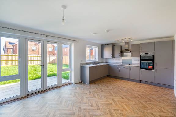 A kitchen with a wooden floor and grey cabinets.