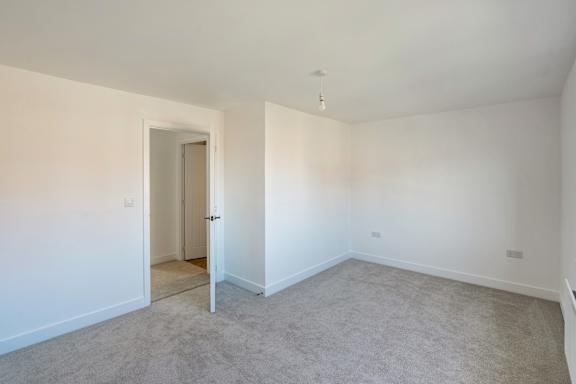 A room with a carpeted floor and a doorway leading to another room.