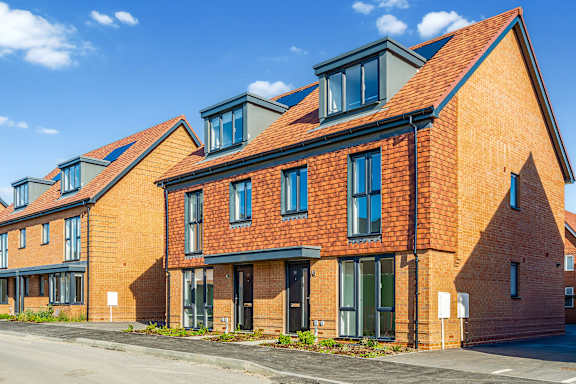 A row of red brick houses with a clear blue sky above.