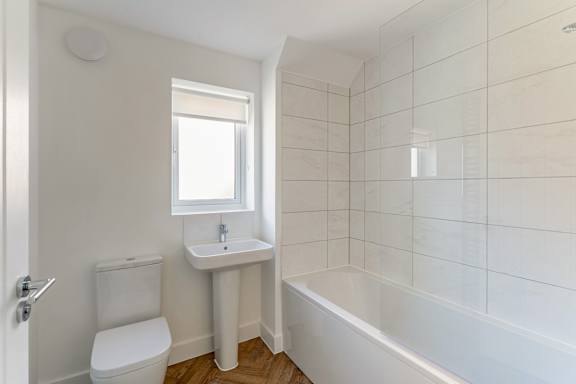 A white bathroom with a toilet, sink, and bathtub.