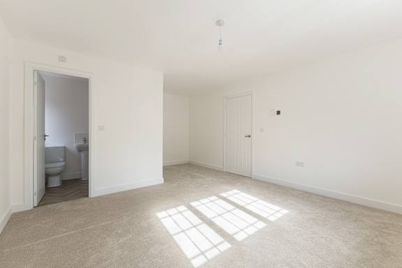 A white room with a toilet visible through an open door.