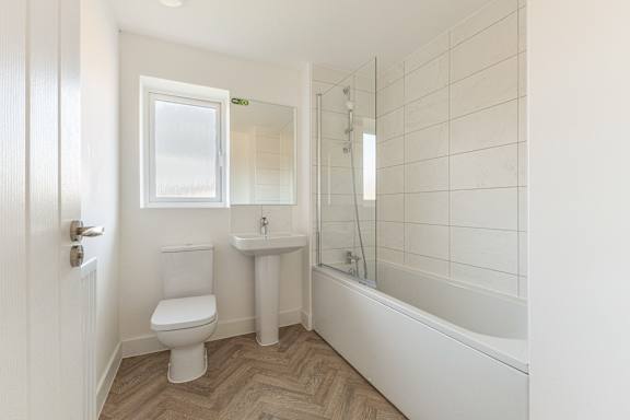 A white bathroom with a toilet, sink, and bathtub.