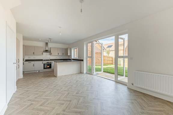 A spacious kitchen and living room with a herringbone patterned floor.