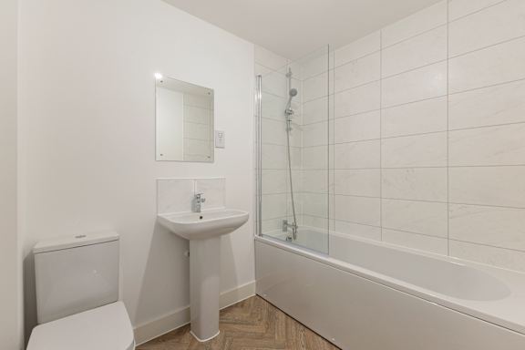 A white bathroom with a toilet, sink, and bathtub.