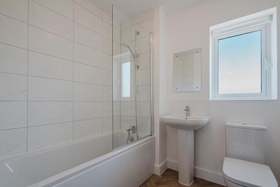 A white bathroom with a tub, sink, and toilet.