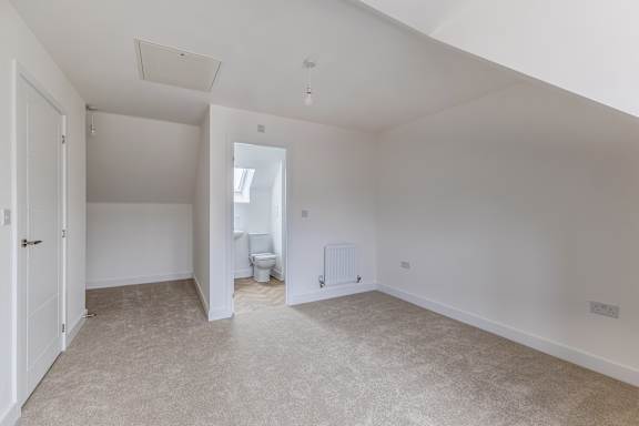 A large, empty room with a toilet visible through the open door.