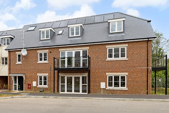 A red brick house with a balcony and solar panels on the roof.