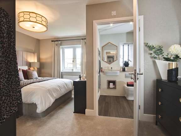 A bedroom with a large bed and a vanity with a mirror.